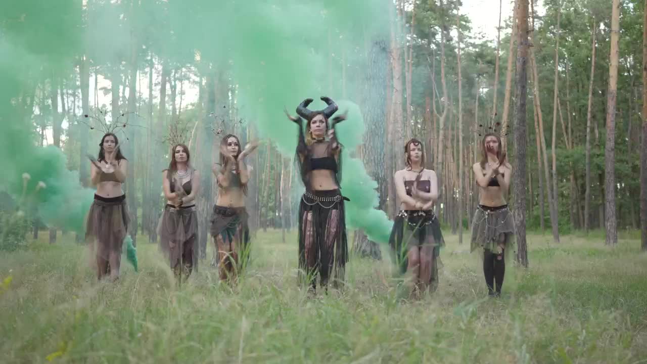 Costumed women belly dance in forest music video