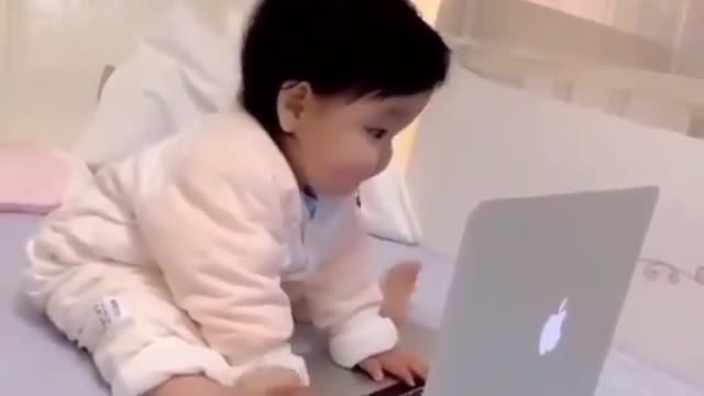 Adorable baby using laptop and doing work .