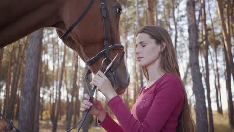 Close-up portrait of a young Caucasian woman caressing horse