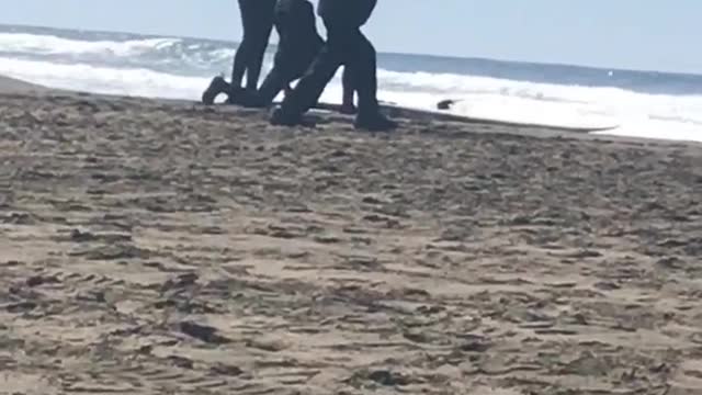 Guy in black jacket and black hat dancing on beach