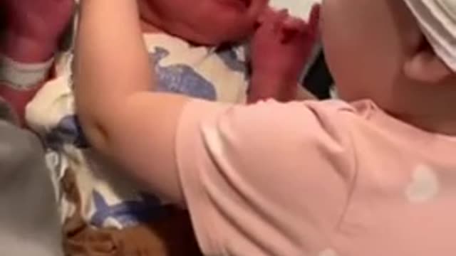 One-year-old girl excitedly meets her newborn baby brother