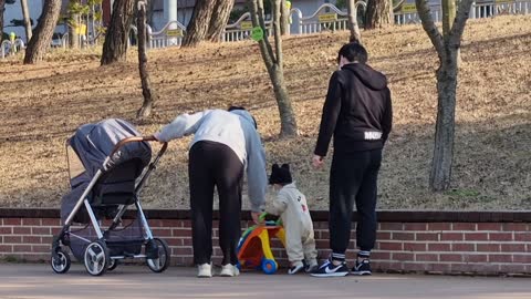 A baby practicing walking with his parents.