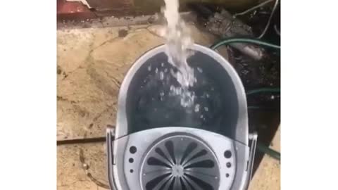 A friend plays a joke on her friend and throws a bucket of water on her on the bed