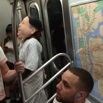Person with head costume and hospital gown dancing in subway