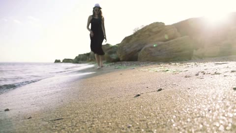 Young woman walking with her puppy dog on the beach during sunset