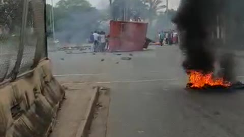 Protestors push a shipping container on the road in Durban