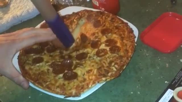 Guy cutting pizza with swiffer handle bar