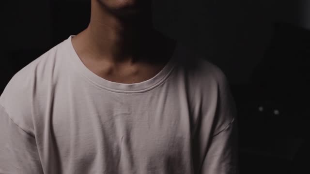 A Man in White Shirt Looking Pensive Against Black Background