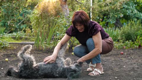 Old woman playing with her dog on the floor