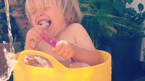 Little boy loves being watered in bucket