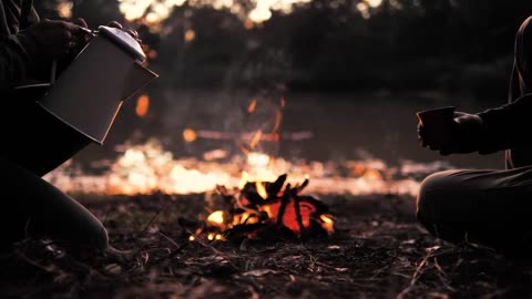 People pouring a warm drink around a campfire