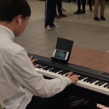Man playing piano while playing games on phone