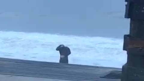 Black wetsuit guy doing stretches on beach