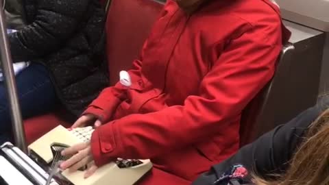 Woman uses typewriter on a subway train