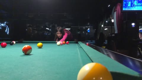 Girl kicks the ball in American billiards.