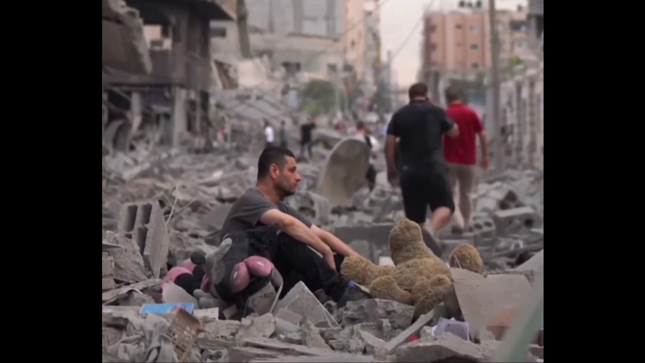 A Palestinian man sits in the middle of the ruins of his house,