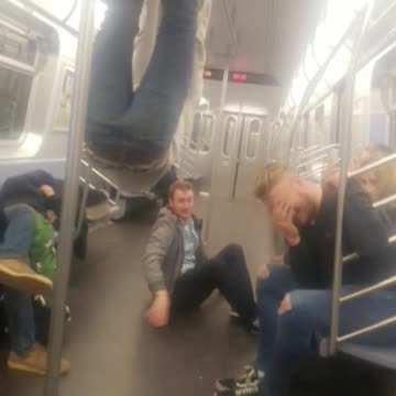 Two guys hanging on subway rails one falls off