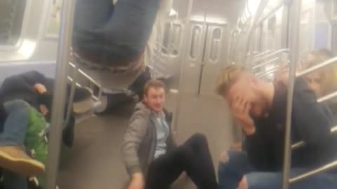 Two guys hanging on subway rails one falls off