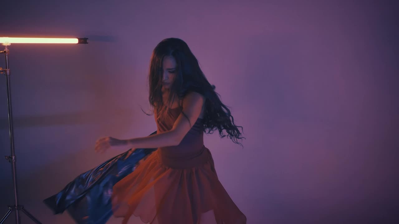 Young woman dancing and spinning in a dark studio