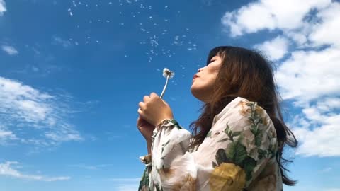 A girl playing with dandelion