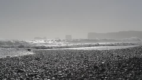 Waves breaking over black sand