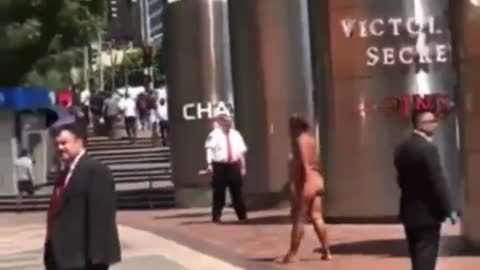 Naked mentally ill person walks around a business district while the rest of us ignore her.