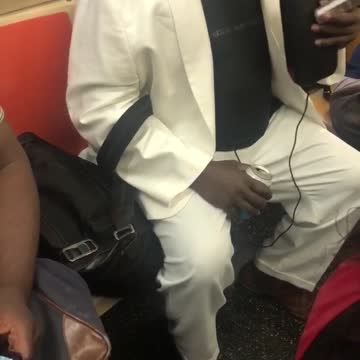 Man in white suit talking into small bag