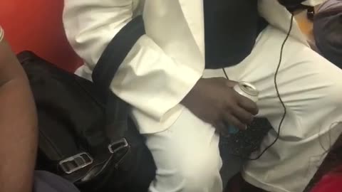 Man in white suit talking into small bag