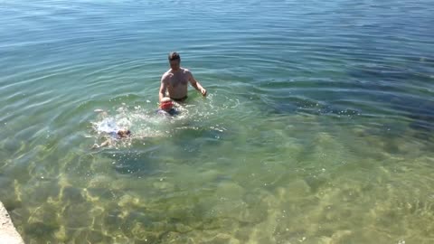 Kids Swim In Pond Along With Their Father And Splash Water At Each Other