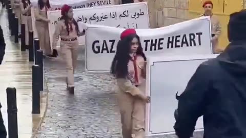 Christmas scouts in Bethlehem march while holding protest signs condemning the Israeli war on Gaza
