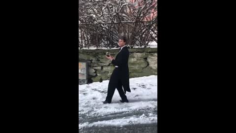 Guy Slides Down Icy Road While Wearing Suit and Holding Wine Glass in his Hand