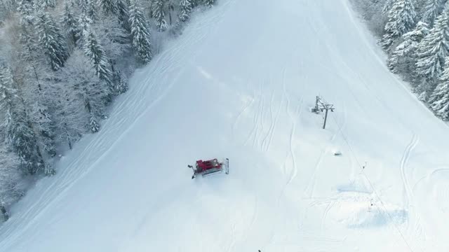 Aerial footage showing a snow-cat snow grooming the ski slopes