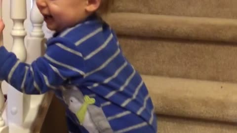 Twin baby extremely amused by brother on stairs