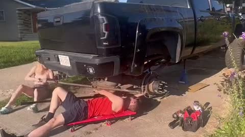 A mechanic repairs a car with his girlfriend