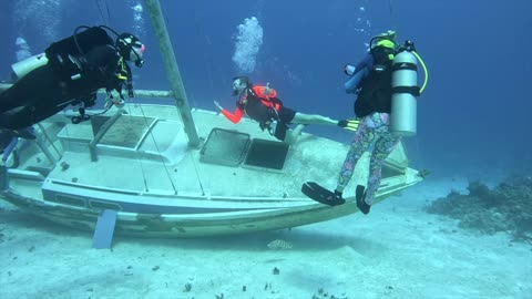 Scuba divers explore a sunken sailboat in the Bahamas