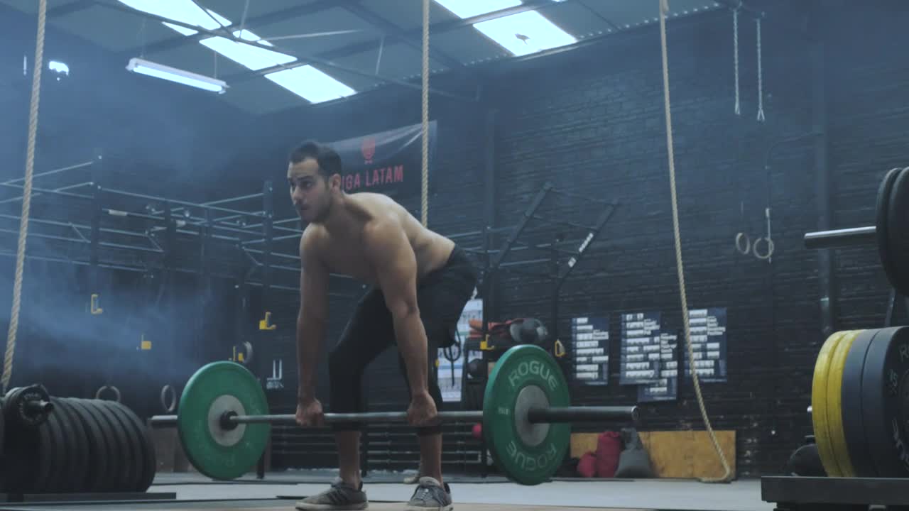 Shirtless man lifting weights at the gym