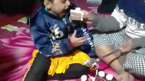 Little girl cutting birthday cake with her brother