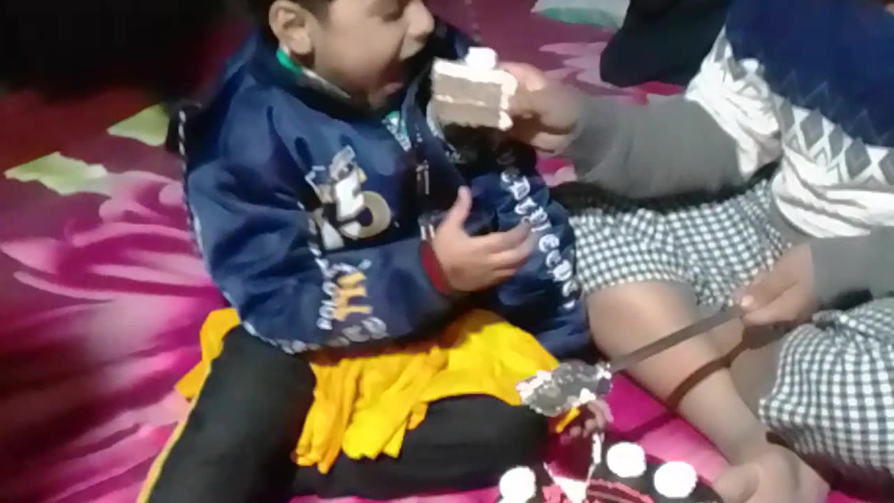 Little girl cutting birthday cake with her brother