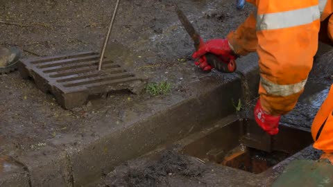 Handheld Close Up Shot of Drainage Worker Attempting to Unblock Drain