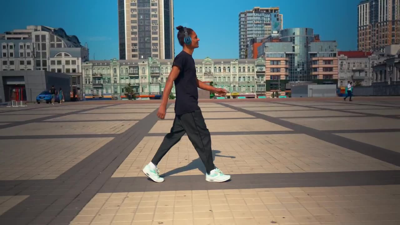 Young man walking listening to music from his headphones.