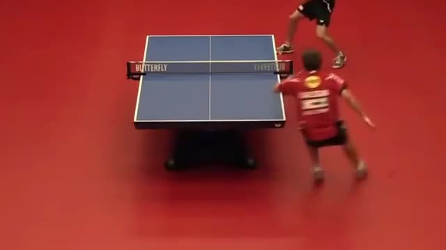 A player in red and a player in black are playing table tennis