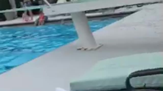 Little boy red swim shorts flips off diving board