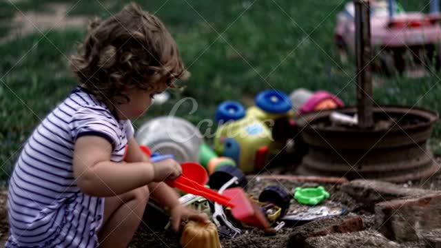 Baby is digging the soil and playing with her toy.