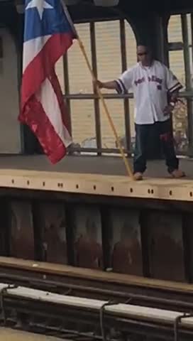 Guy standing on train platform with huge big flag