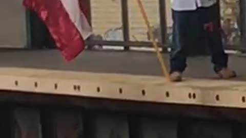 Guy standing on train platform with huge big flag