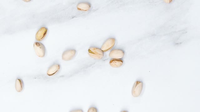 Spreading Widely A Handful Of Pistachio Nuts Over A Marble Surface