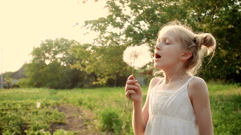 Girl blowing a dandelion flower