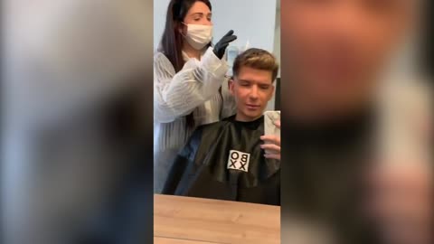 Student gets hair cut by hairdresser in a 'Coronavirus suit'