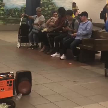 Guy red shirt black hat dancing sits between people subway bench
