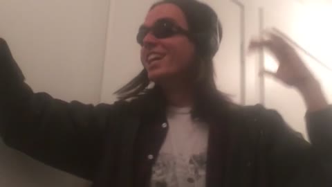 Music guy in black headphones and white shirt shakes head to song